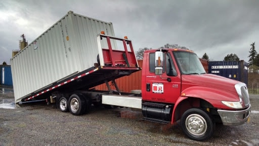 Tilt-bed truck delivering a 20-foot shipping container